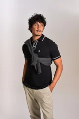 Polo de manga corta confeccionado en tejido interlock suave, color negro con detalles de vivos en color blanco en el cuello y las mangas. Presenta tapeta con botones y un bolsillo frontal con el logo bordado.