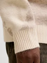 Sweater de punto con diseño estampado, cuello redondo, manga larga y ajuste relajado. Presenta puños y ruedo acanalados, ofreciendo una textura suave y elástica.
