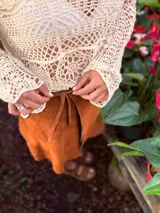 Buzo tejido color crudo con mangas largas y calado en el frente.