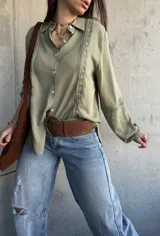 Camisa de manga larga color verde militar con inserciones de encaje decorativo en el frente y las mangas, cuello camisero y cierre frontal de botones.