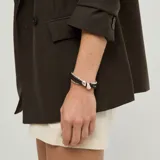 Pulsera de cuero marrón oscuro y cuentas metálicas plateadas, con diseño multicapa y detalles de piezas metálicas con forma orgánica.