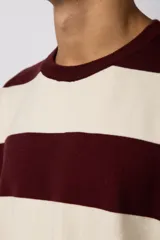 Remera de tejido de punto con diseño de rayas horizontales anchas en color bordó y crema, de corte holgado y cuello redondo.