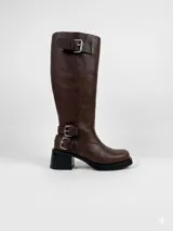 Bota de caña alta estilo biker, confeccionada en cuero negro. Presenta tres hebillas metálicas decorativas, cierre lateral y taco de madera.