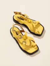 Sandalia baja de cuero vacuno con tiras cruzadas y aplique decorativo. Tiene hebilla en el talón y empeine para regular el calce.