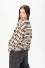 Sweater de punto fino con diseño de rayas horizontales en tonos marrón y blanco, de manga larga y corte holgado con hombros caídos.