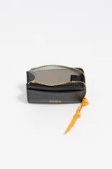 Monedero o tarjetero pequeño de cuero rojo, con cierre de cremallera superior y un tirador de tela a juego. Presenta un bolsillo exterior frontal y el logo de la marca grabado en dorado.