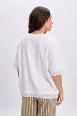 Remera manga corta de color blanco con detalles de encaje en el borde de las mangas y el ruedo, de corte holgado y diseño casual.