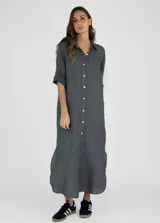 Vestido camisero largo de lino, color mostaza, con cuello camisero, cierre frontal de botones y mangas tres cuartos con detalle de tejido calado en los laterales.