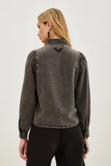 Camisa de liocel color gris oscuro con bordado de flores negras en las mangas largas abullonadas.