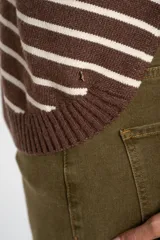 Sweater marrón con rayas horizontales blancas, de corte holgado y manga larga. Tejido suave y liviano de viscosa, poliéster y poliamida.