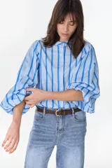 Camisa de manga larga abullonada con diseño a rayas verticales celestes y azules, cuello mao y cierre frontal con botones ocultos.