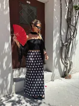 Falda larga negra con lunares blancos, corte al bies y tajo lateral.