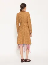 Trench marrón claro con broderie y detalles en cuero marrón, con hombreras, bolsillos plaqué con tapa de cuero y lazo para ajustar en cintura.