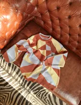 Sweater de punto con diseño geométrico en tonos celeste, marrón y beige.