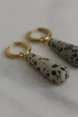 Aros tipo argolla con dije colgante en forma de gota de piedra natural en tonos marrones. Fabricados en acero quirúrgico dorado.