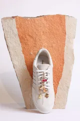 Zapatillas bajas color marrón con cordones y charms dorados.