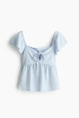Blusa corta celeste de punto pointelle con textura, escote corazón, mangas cortas con vuelo y cordón de ajuste en el centro del busto.