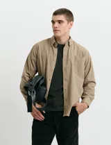 Camisa de franela lisa con cuello button-down, manga larga, botones al tono y bolsillo frontal en el pecho.