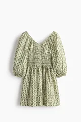 Vestido corto de algodón con estampado geométrico en tonos verdes y blancos. Cuenta con escote en V, mangas globo con elástico en los puños, cuerpo fruncido tipo nido de abeja en la cintura y falda con vuelo.