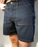 Bermuda de jean negra con dos bolsillos frontales tipo parche, costuras a contratono color ocre y botón de cobre.