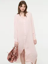 Camisa larga de corte oversize, color rosado, con cuello camisero, cierre frontal con botones y mangas largas.