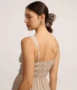 Vestido corto de silueta evasé color celeste, con escote recto y detalle de lazo en el centro. Posee breteles medianos, cintura elástica fruncida y falda con volados escalonados.