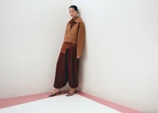 Chaqueta de corte recto color tostado, con cuello camisero, manga larga, dos bolsillos de parche con solapa en el frente y cierre frontal de botones oscuros.