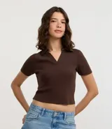 Blusa de cuello polo y manga corta, confeccionada en tejido rib de algodón con elastano. Presenta un diseño ajustado al cuerpo con escote en V y textura acanalada.