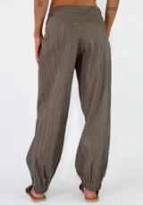 Pantalón beige con textura arrugada, de corte holgado estilo balloon con puños elásticos en los tobillos y cintura alta con faja y lazo ajustable.