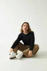 Sweater negro de punto con diseño trenzado, corte cropped, cuello redondo y mangas largas.