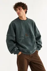 Buzo oversize de corte unisex, color rojo con efecto desgastado (acid wash), confeccionado en algodón con interior de polar. Presenta costuras frontales decorativas, hombros caídos, mangas largas con puños elastizados, rib en el cuello y el ruedo, y un pequeño logo bordado en el pecho.