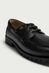 Zapato estilo náutico de piel color negro, de la colección especial Fruit of the Loom x Zara. Presenta detalle de bordón en el empeine, ojalillos metálicos dorados, cordones negros y suela track dentada.