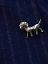 Pin metálico con forma de perro, con acabado plateado y diseño detallado.