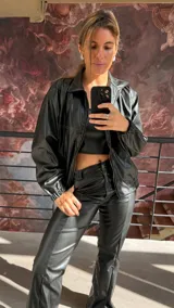 Campera bomber negra de cuero sintético con cierre frontal, cuello clásico y puños elásticos.