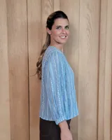 Camisa de manga larga con diseño de rayas verticales y bordados sutiles. Presenta cuello redondo, cierre frontal con botones y mangas abullonadas con volados en los hombros.