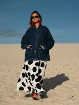 Campera de jean azul oscuro, de corte oversize, con cuello clásico, cierre frontal con botones metálicos, bolsillos con solapa en el pecho y estampado de lunares grandes en blanco y negro en la espalda.