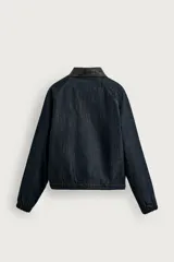 Cazadora de corte relajado confeccionada en tejido denim de algodón sin lavados, con ligero acolchado interior. Presenta cuello solapa en tejido efecto piel a contraste, cierre frontal de cremallera, bolsillos de vivo en la cadera y puños elásticos.