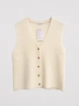 Chaleco tejido de punto waffle color crema, con escote en V y cierre frontal mediante botones metálicos dorados. Presenta un diseño de corte recto y sin mangas.