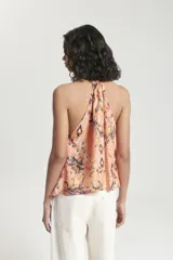Top sin mangas con escote halter y abertura frontal. Presenta un diseño estampado multicolor, con ruedo irregular y detalle de bretel ajustable en el cuello.