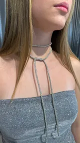 Gargantilla larga tipo lazo confeccionada en strass plateado, diseñada para anudar al cuello.