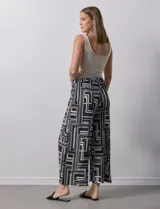 Pantalón ancho estilo palazzo, de seda fría plisada con estampado geométrico en negro, blanco y beige. Tiene pretina ancha elastizada y largo crop.