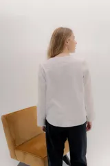 Remera de manga larga con escote a la base, color blanco, con un bordado central de dos líneas negras verticales en la parte delantera. La parte delantera es de lino y la espalda de algodón con spandex.