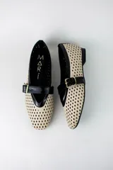 Guillerminas flat de ecocuero color beige con diseño calado en rombos y detalles en negro charol en la puntera y tira con hebilla dorada.