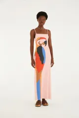 Vestido largo rosado de silueta recta y diseño sin mangas con finos breteles y escote cuadrado. Cuenta con un llamativo estampado frontal de un guacamayo en tonos rojo, azul, amarillo y negro.