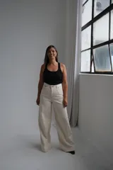 Jean de corte wide leg en color crudo, con tiro alto y costuras reforzadas en contraste. Presenta diseño de cinco bolsillos y cierre frontal con botón metálico.