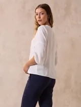 Blusa de gasa con estampado geométrico en tonos negro, gris y celeste. Tiene cuello redondo y mangas 3/4 amplias con abertura y botón.