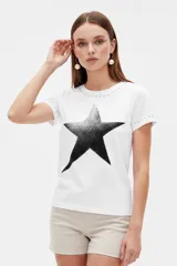 Remera de manga corta color blanco con cuello redondo, corte ajustado al cuerpo y estampa frontal de estrella con degradado. Cuenta con detalles de tachas metálicas en el cuello y en los puños.