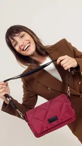 Bandolera capitoneada color bordó, con bolsillo interno, correa de galón ajustable y tapa con broche.