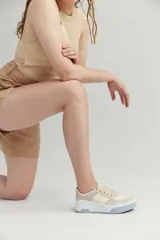 Zapatillas bajas de cuero sintético color crema con detalles en verde pastel y suela celeste.