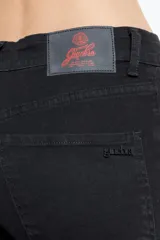 Jean negro de denim elastizado, de calce high skinny, tiro alto, avios marcarios negros y chapita Ginebra en el bolsillo trasero.